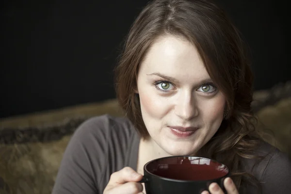 Mujer joven con hermosos ojos verdes y taza de café negro — Foto de Stock