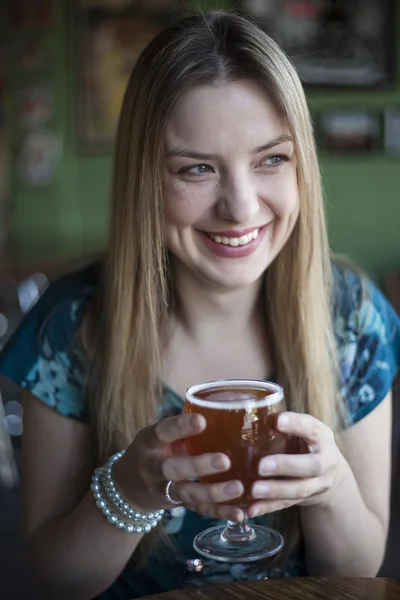 Blond kvinna med vackra blå ögon dricker en bägare öl — Stockfoto