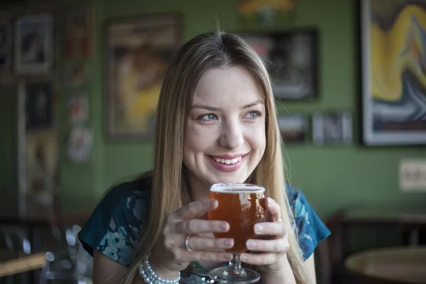 Blond kobieta z piękne niebieskie oczy pije kielich piwa — Zdjęcie stockowe