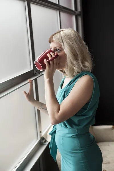 Bella giovane donna che beve dalla tazza di caffè rosso — Foto Stock