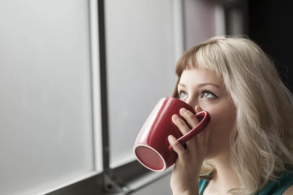 Mooie jonge vrouw drinken uit de rode koffiekopje — Stockfoto