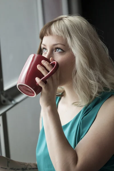 Belle jeune femme buvant de la tasse de café rouge — Photo