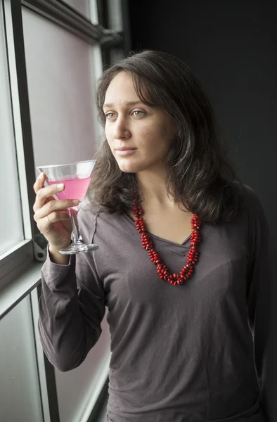 Mladá žena s krásné zelené oči pití růžové martini — Stock fotografie