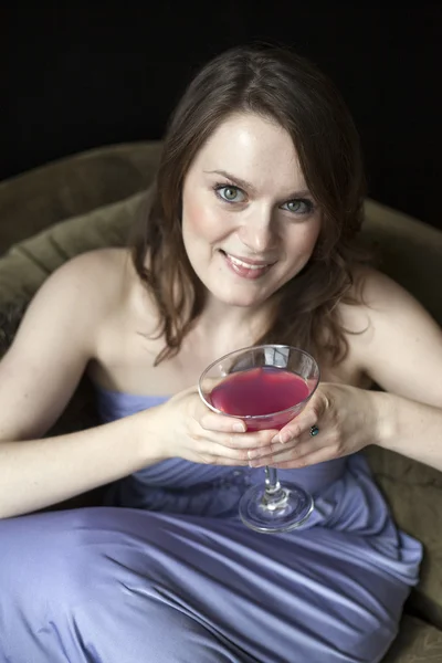 Молодая женщина с красивыми зелеными глазами пьет розовый мартини — стоковое фото