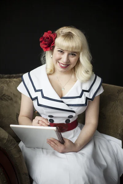 Mooie jonge vrouw met blond haar schrijven in haar notitieblok — Stockfoto