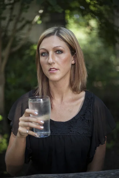 Blond kvinna med vackra blå ögon och glas vatten — Stockfoto