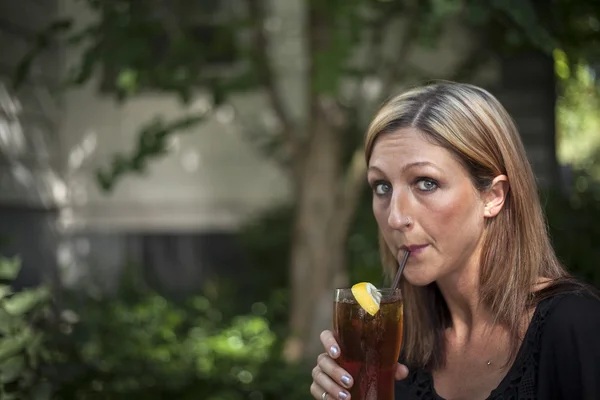 Blonde Woman with Beautiful Blue Eyes and Glass of Iced Tea