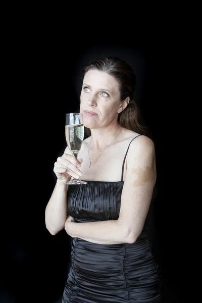 Středního věku žena v černých šatech s champagne — Stock fotografie