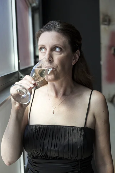 Średniej wieku kobieta w czarnej sukni z szampanem — Zdjęcie stockowe