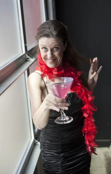 Женщина средних лет в черном платье с розовым мартини — стоковое фото