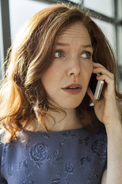 Молодая женщина с красивыми голубыми глазами разговаривает по мобильному телефону — стоковое фото