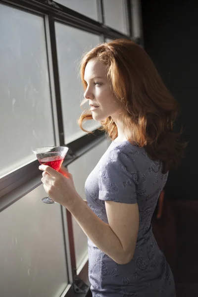 Mujer joven con hermosos ojos azules y cabello rojo bebiendo un rojo — Foto de Stock