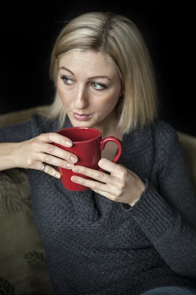 Femme blonde avec de beaux yeux bleus et tasse de café rouge . — Photo