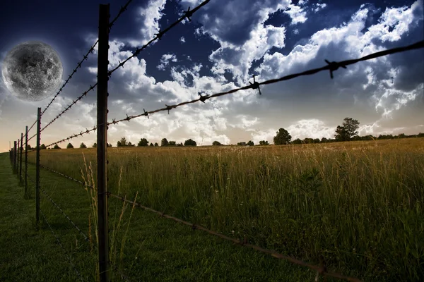 Moln på himlen och jordbrukare staket i fältet — Stockfoto
