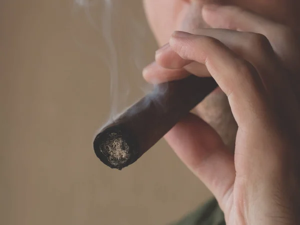 A man smokes a Cuban cigar. Close-up of a smoking cigar.