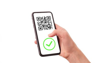 Kadının elinde beyaz arka planda aşı sertifikası olan bir telefon var. Akıllı telefonda QR kodu ve yeşil kontrol işareti