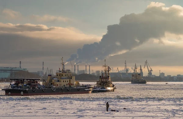 Bir balıkçı donmuş bir nehirde balık yakalar ve gemilere bakar. Nehirde kış seyrüsefer. Buz balıkçılığı.