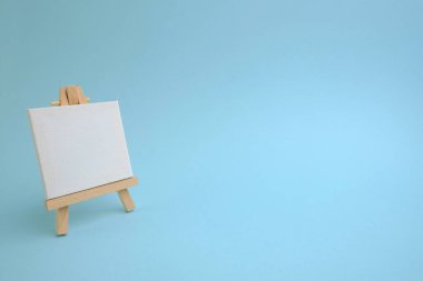 Mavi arka planda ahşap sehpası olan boş bir kağıt.