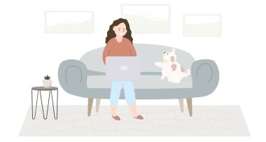 Evde resimde dizüstü bilgisayarla kanepede oturan kedili genç bir kadın.