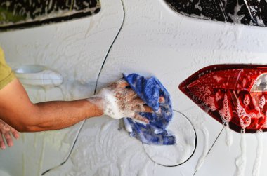 Beyaz SUV 'nin fotoğrafını yıkayan adamın eli.