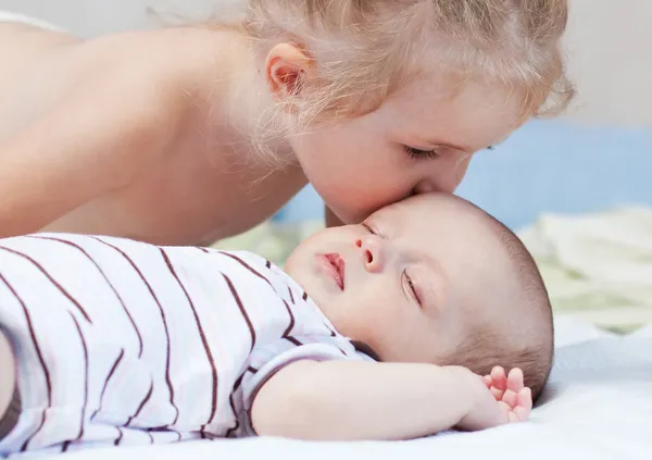 Irmãzinha beijando bebê irmão — Fotografia de Stock