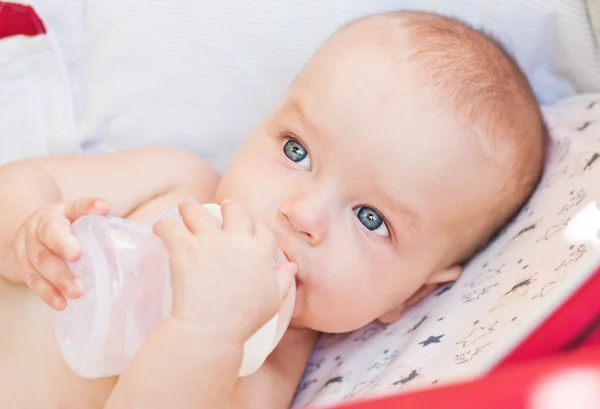 Bebé sosteniendo un biberón y beber agua —  Fotos de Stock