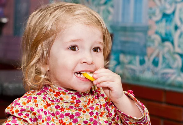 Милая маленькая девочка ест лимон — стоковое фото