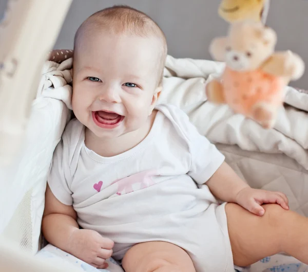 Happy baby sitting in bed — Stock Photo, Image