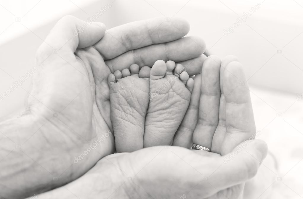 Feet newborn baby in father's hands