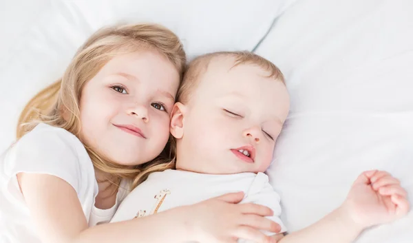 Carino bambina abbraccia un dormire bambino fratello — Foto Stock