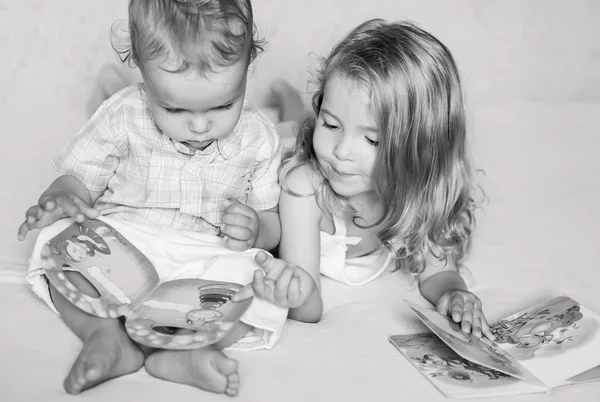 Lillebror och syster tittar på en bok — Stockfoto