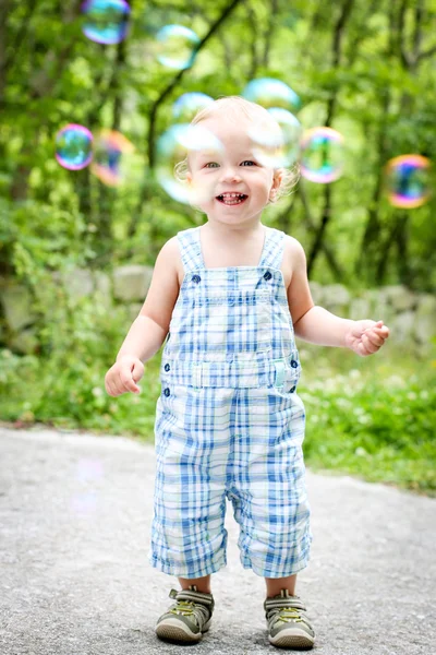 Menino feliz olhando para bolhas — Fotografia de Stock