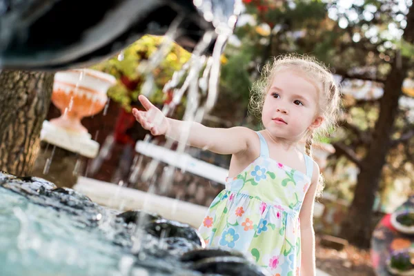 Söt liten förskolebarn flicka spelar med staden fontän — Stockfoto