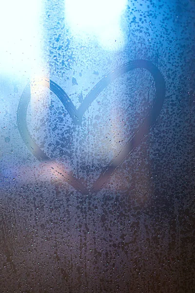 A heart drawn on a misted glass with water drops. — Stock Photo, Image