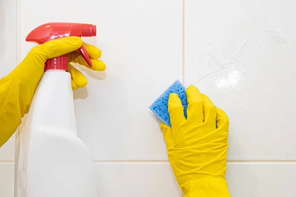 Ruce ve žlutých gumových rukavicích mytí dlaždic v koupelně. Stock Fotografie