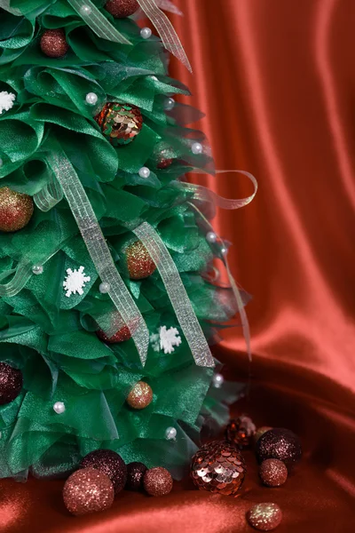 Рождественская ёлка ручной работы на красной драпировке — стоковое фото