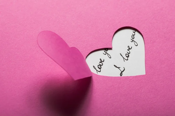 Srdce polovině cut z růžového papíru — Stock fotografie