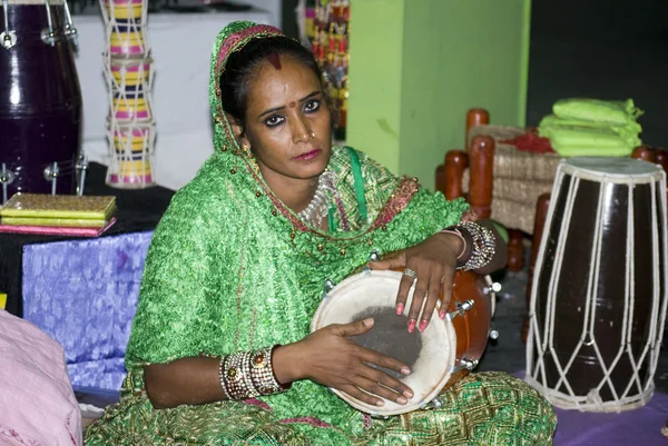 A tribal woman from Rajasthan playing a percussion instrument