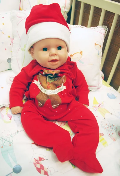 En baby docka med jul cap liggande i en krubba med kuddar Stockbild