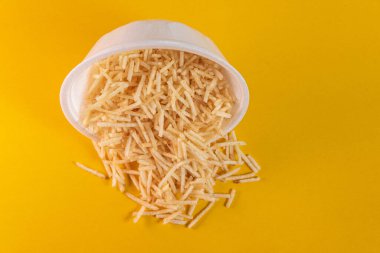 Sarı arka planda patates kamışlı beyaz kase.