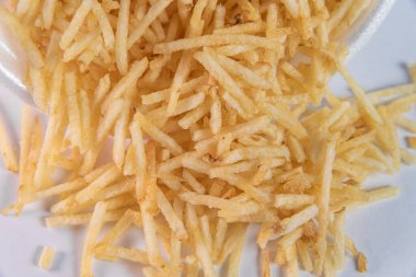 Beyaz arka planda patates kamışı olan beyaz kase.