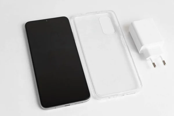 隔離された白い背景に透明カバー付きの新しい携帯電話と充電器 — ストック写真