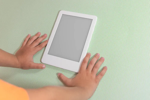 Ebook reader over green background - being held by the hand of a child
