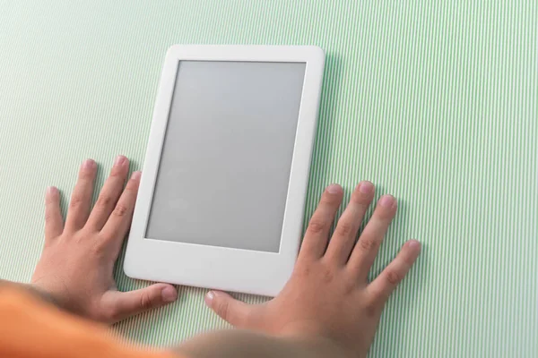 Ebook reader over green background - being held by the hand of a child