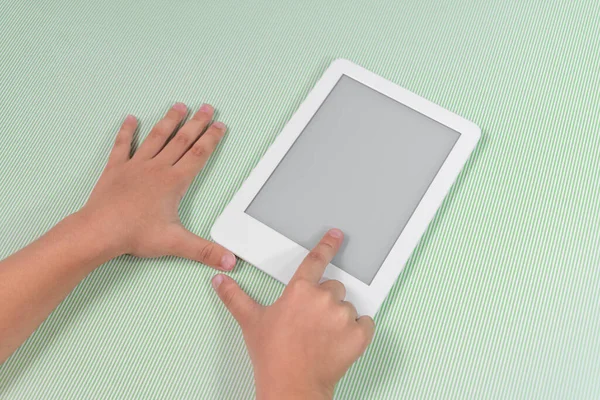 Ebook reader over green background - being held by the hand of a child