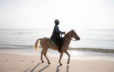 PRACHUAP KHIRI KHAN, THAILAND- 15 Nisan 2021: Tanımlanamayan insanlar sabahın erken saatlerinde Huahin sahilinde Tayland 'daki Prachuap Khiri Khan plajında ata biniyorlar.