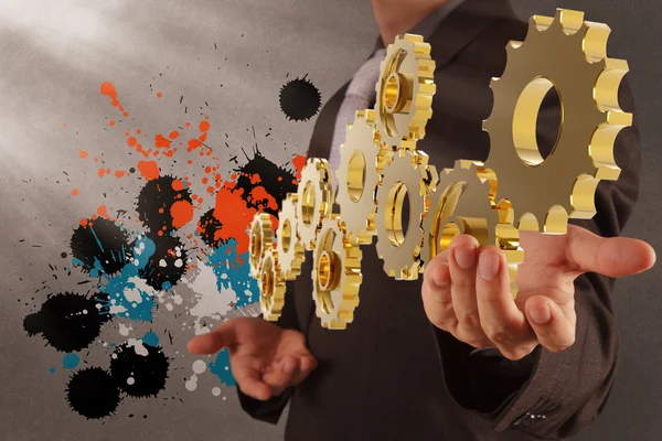 Businessman working with gear and splash colors — Stock Photo, Image