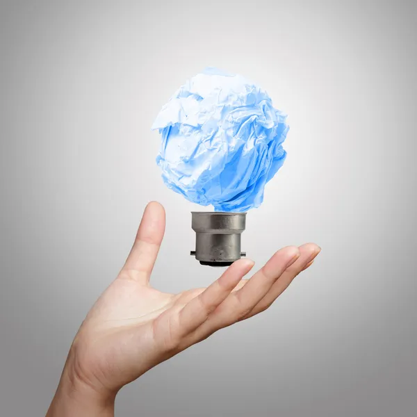 Hand showing light bulb crumpled paper — Stock Photo, Image