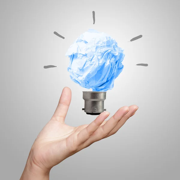 Hand showing light bulb crumpled paper — Stock Photo, Image