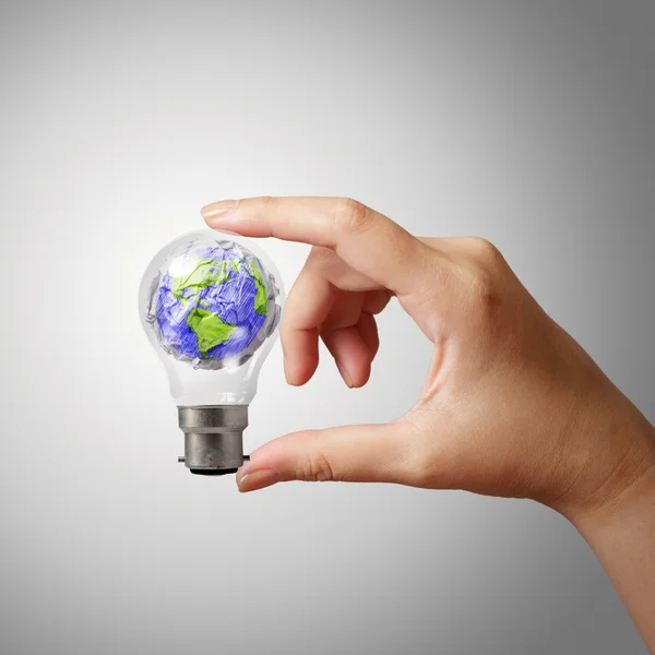 Hand showing crumpled world paper symbol in light bulb — Stock Photo, Image